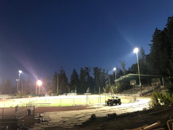 Football field lights on with dark sky night